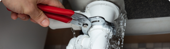 Plumber tightening leaky pipe with wrench