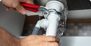 Plumber tightening leaky pipe with wrench